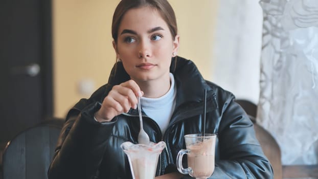 Teenage girl sipping hot chocolate, indulging sweet pastry at rustic cafe, relaxing during afternoon leisure moment