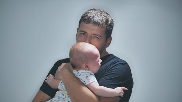 Young father holding his crying baby, expressing deep concern for the child's health and well being while navigating the challenges of parenthood