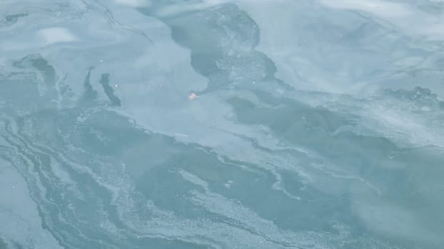 Oil spill forming abstract patterns on the surface of the ocean, highlighting the devastating effects of pollution on marine ecosystems