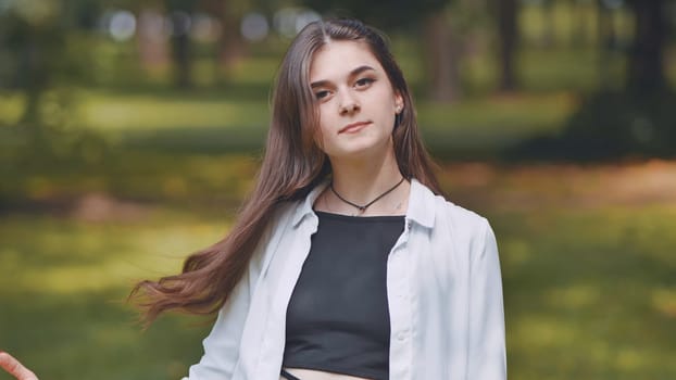 Portrait of a young georgian woman posing in a green park, wearing a white shirt and black top