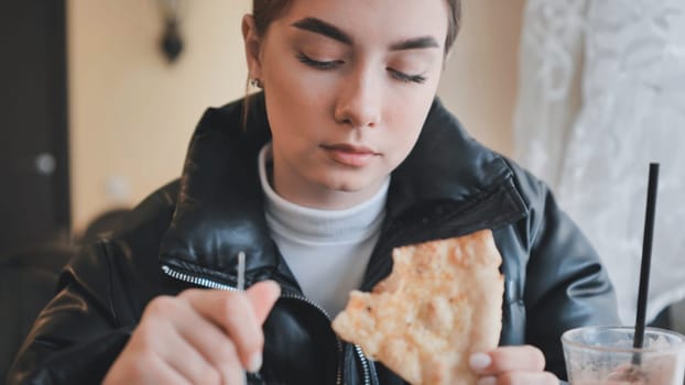 Young woman savoring a slice of pizza in a casual dining setting, enjoying a relaxed meal
