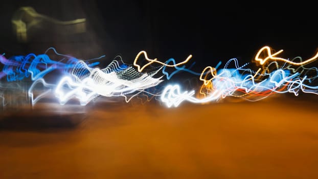 Colorful light trails streak across a dark background, creating a vibrant abstract composition of motion and energy