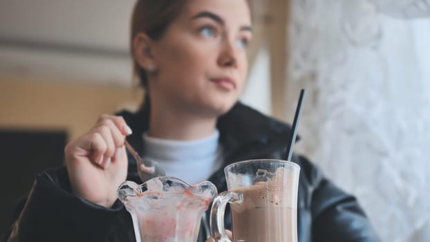 Customer is eating strawberry ice cream and drinking iced coffee in a cafe, enjoying a sweet treat