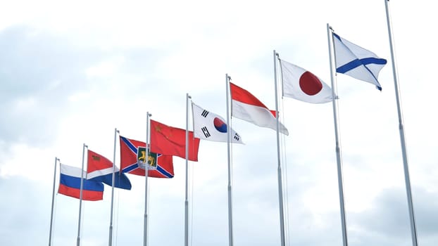 National flags fluttering together, symbolizing global unity and international collaboration within cloudy atmospheric backdrop