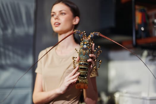 Woman holding lobster in kitchen setting, preparing for seafood feast