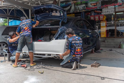 Bangkok, Thailand - April 4, 2024 : Unidentified denter or car mechanic serviceman check and fix body work and fiber bumper body part for fix and repair problem at car garage or repair shop