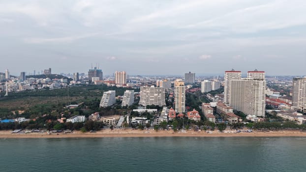 Modern buildings rising along the pattaya coastline create a stunning cityscape against the ocean backdrop as twilight approaches, blending urban development with natural beauty