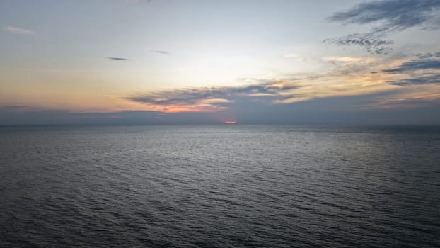 Vibrant sunset colors painting the sky with hues of orange, pink, and purple over a calm ocean, creating a serene and tranquil atmosphere perfect for relaxation and reflection