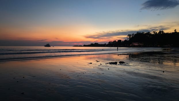 Stunning sunset colors painting the sky over a tranquil beach, with the wet sand reflecting the vibrant hues and a yacht sailing peacefully on the calm sea, creating a serene and picturesque scene