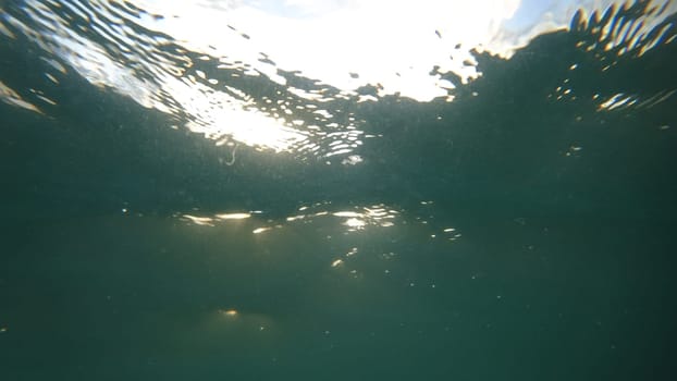 Sunlight filters through the surface of a body of water, creating a mesmerizing underwater scene with dancing light beams and gentle ripples