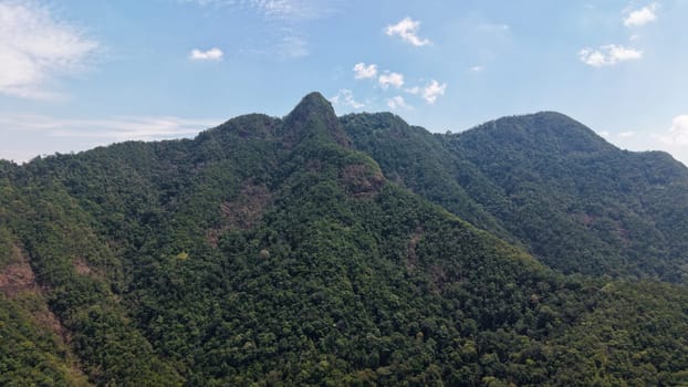 Impressive mountain peaks covered in lush green vegetation rise towards a bright blue sky dotted with white clouds, creating a breathtaking landscape in sri lanka