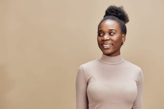 Confident Black woman in a beige turtleneck smiling warmly, set against a natural brown backdrop, ideal for health, beauty, and lifestyle themes