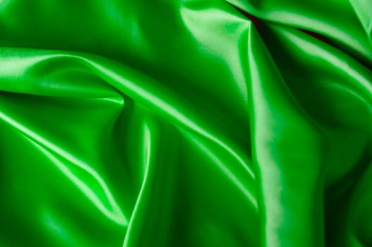 Shining green satin textile with shimmering highlights. Suitable for design and wallpaper background.
