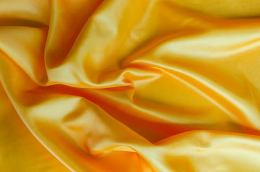 Golden yellow satin textile with shimmering highlights. Suitable for design and wallpaper background.
