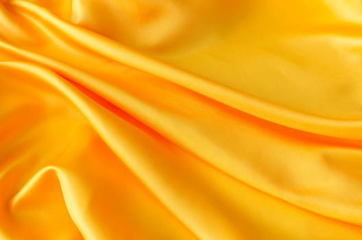 Top view of elegant yellow satin textile with shimmering highlights. Suitable for design and wallpaper background.