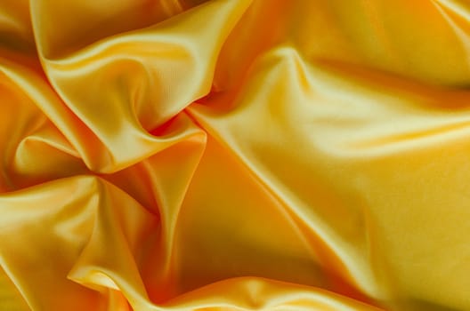 Top view of golden yellow silk with curves and vibrant reflective surface. Suitable for design and wallpaper background.