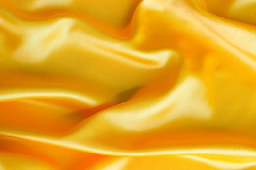 Close up of glossy yellow satin material with smooth surface and folds. Suitable for design and wallpaper background.