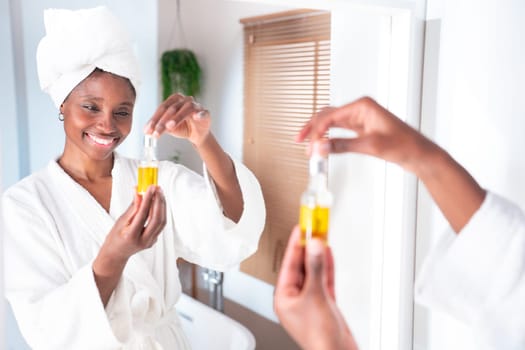A woman happily applies facial oil in her cozy bathrobe, emphasizing selfcare, skincare, and wellness