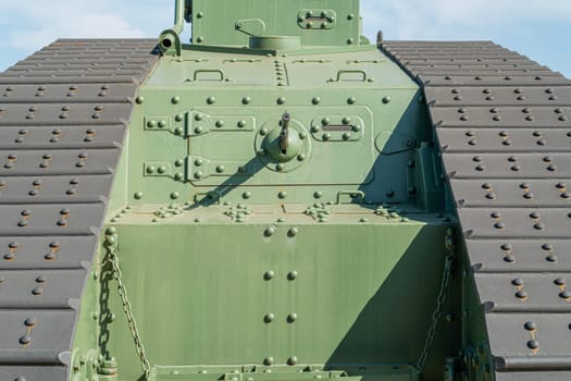 Bright sunlight reveals the intricate details of a military tank's armor design.