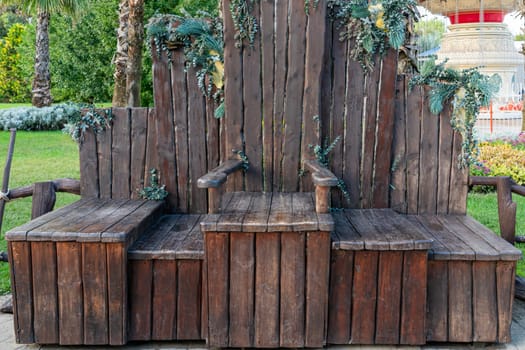 A unique wooden bench with natural foliage embellishment is situated in a vibrant garden. The tranquil atmosphere creates a perfect spot for relaxation among the greenery.