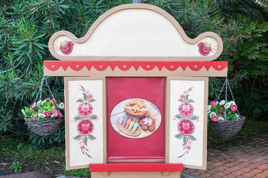 A charming decorative stand showcases an assortment of cookies on a plate, adorned with floral artwork and accompanied by hanging baskets filled with flowers.