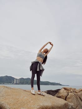 A fit young woman in athletic clothing stretches against a scenic beach backdrop, reflecting health and wellness Perfect for fitness and lifestyle themes