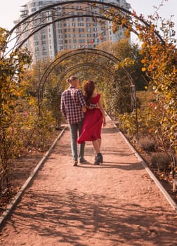 Happy young couple in love spending time together in autumn park hugging. Romantic couple enjoying moments of happiness in city park. Love and tenderness, dating, romance. Lifestyle concept. back view