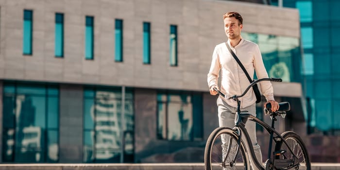 A young man strolls along a city street, casually holding onto his bike. He wears light clothing and exudes a relaxed vibe, reflecting the millennial lifestyle, copy space
