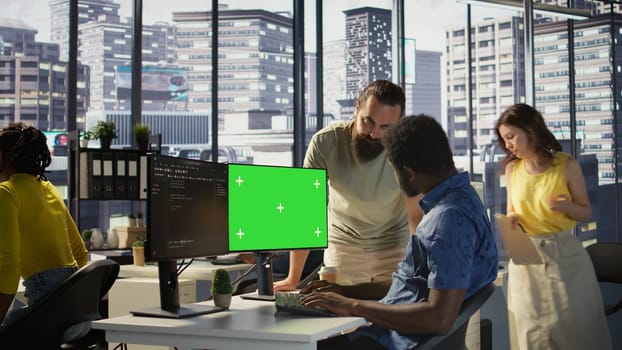 System administrator does software debugging on isolated screen PC, asking for help from coworker. Zoom in on admin fixing coding mistakes on chroma key computer, being assisted by colleague, camera B