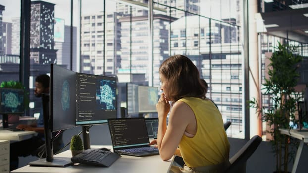 Hacker in office using laptop to steal company secrets, doing data breach, hiding from manager. Employee hired by competitor to spy, mining info from servers, closing notebook lid to hide, camera B
