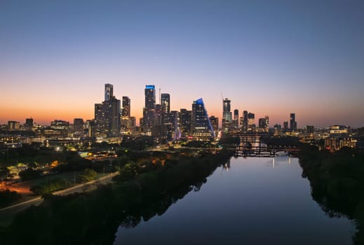 Brilliant orange and red sky behind the illuminated city skyline of Austin Texas before sunrise dawn