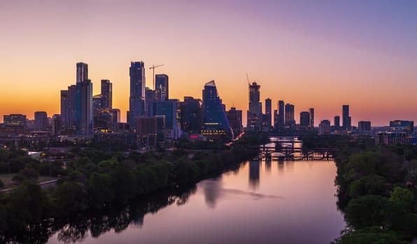 Brilliant orange and red sky behind the illuminated city skyline of Austin Texas before sunrise dawn