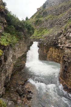 Stunning waterfall cascading into a turquoise pool nestled within a rocky gorge, creating a breathtaking natural landscape filled with vibrant colors and serene beauty