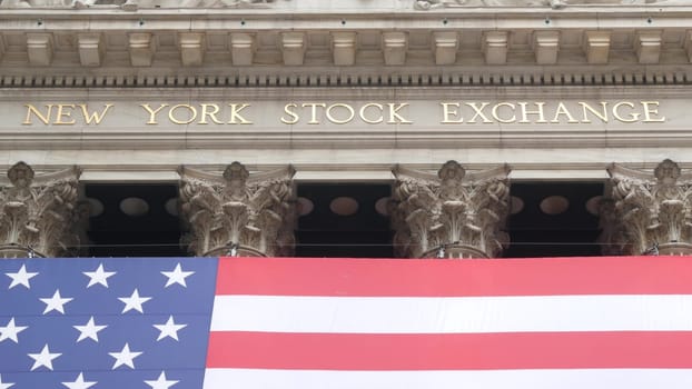 New York City, United States - 9 Sept 2023: Lower Manhattan Downtown Financial District urban architecture. Huge big American flag. Wall street Stock Exchange building, USA Stock Market trading.