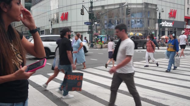 New York City, United States - 29 Aug 2023: Manhattan Midtown 34 street. Herald Square, Broadway, Sixth 6 Americas avenue, USA. Road traffic. People on zebra crosswalk. Shopping Mall, Yellow taxi cab.