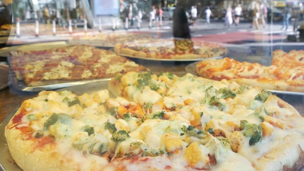New York City, United States - 4 Sept 2023: Manhattan Midtown 42 street. Fast food big large american pizza, pizzeria restaurant counter. People pedestrian and car traffic reflection, USA. Urban life.