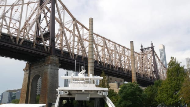 New York City, United States - 12 Sept 2023: Queensboro bridge to Queens, from ferry boat. Manhattan midtown from ferryboat. East river waterfront, riverfront architecture. Pier on Roosevelt Island.