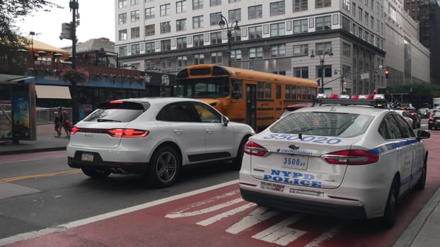 New York City, United States - 29 Aug 2023: Yellow School Bus on Manhattan 34 street, schoolbus and police car on 8 avenue. Children education, road transportation, NYPD USA. American school shuttle.