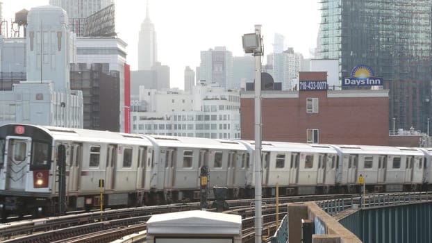 New York City, United States - 2 Sept 2023: Subway station. Metro train public transportation platform. Elevated outdoor railway, Queens passenger railroad traffic, Long Island. Empire State building.