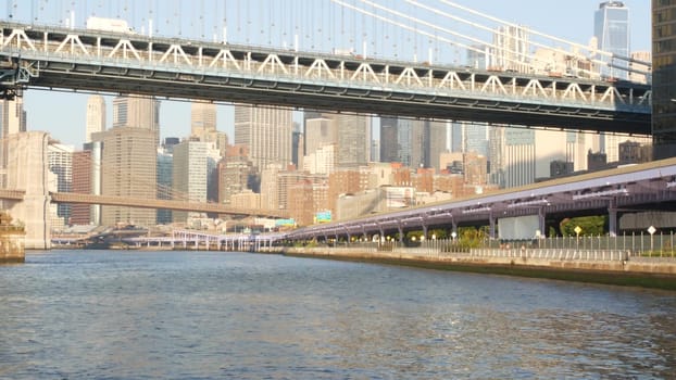 New York City, United States - 7 Sept 2023: Manhattan Bridge to Brooklyn. Waterfront downtown skyline cityscape, financial district skyscrapers from riverfront Pier 35. East river morning sunset.