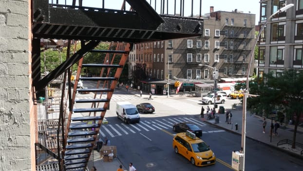 New York City, United States - 1 Sept 2023: Building architecture. Urban residential house exterior, brick facade. Fire escape ladder. Chelsea high line, 10 avenue. Street crossroad. Yellow taxi cab.