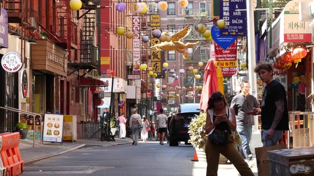 New York City, United States - 14 Sept 2023: Manhattan Chinatown Pell street. Chinese culture, ethnic district architecture, USA. Red brick buildings, round paper lanterns and hieroglyph signs. People