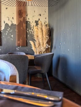 Saint-Petersburg, Russia - 04.16.2024. Stylish restaurant interior with chairs and decorative pampas grass against a textured wall. A warm, inviting atmosphere suitable for dining.