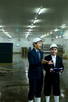 Two factory executives discussing operations inside a food manufacturing facility.