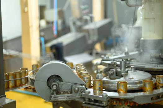 Industrial food production line with metal cans being filled and sealed in a modern facility.