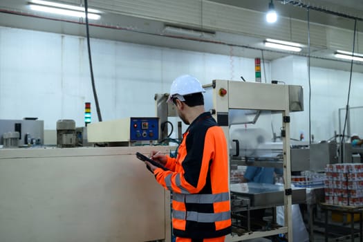 Factory technician monitoring food processing machinery in an industrial facility.
