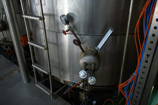 Stainless steel industrial tank with temperature and pressure gauges in a food processing facility.