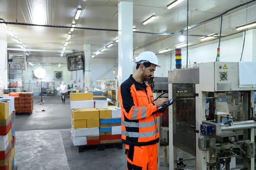 Factory technician monitoring food processing machinery in an industrial facility.