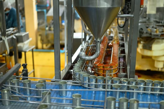 Automated factory line filling metal cans with food product in an industrial processing plant.