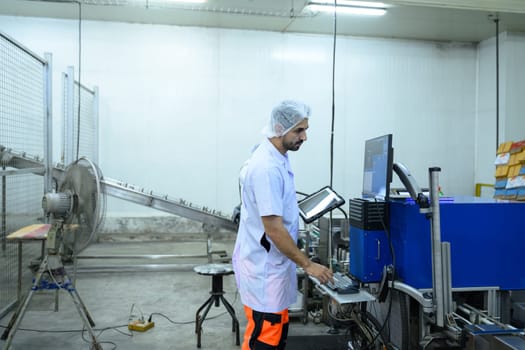 Food factory worker operating machinery via computer system in a modern manufacturing.